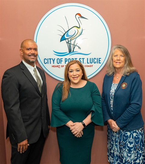 Photo shows three people standing in front of the City of Port St. Lucie logo: Finance Director Stephen Okiye, Vice Mayor Jolien Caraballo, Councilwoman Stephanie Morgan, from left to right.